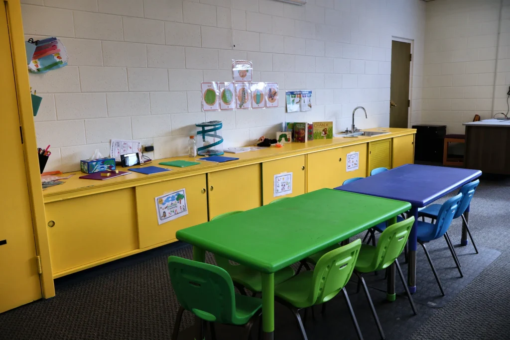 Kidney-shaped activity tables, sink and shelves in a Hand in Hand ABA classroom