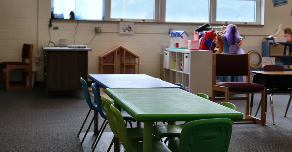 Green and blue child-size activity tables with yellow cabinets in a Hand in Hand ABA classroom