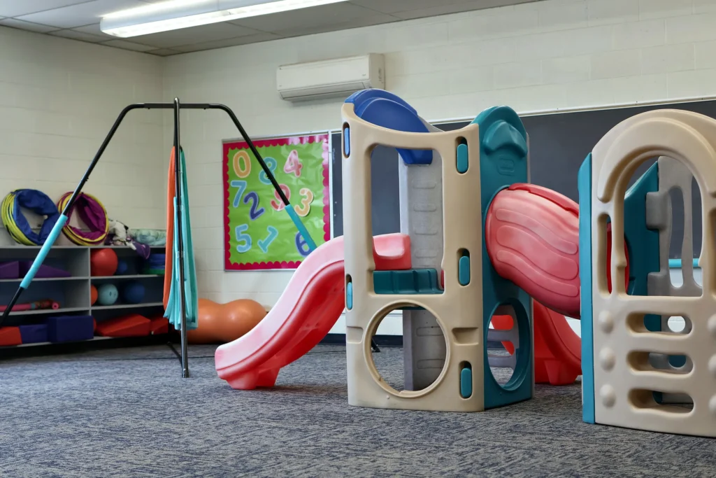 Indoor play structure with slides in the Hand in Hand ABA motor room