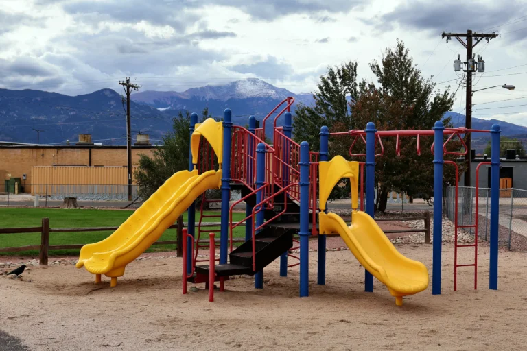 Outdoor playground at Hand in Hand ABA with slides and Pikes Peak in the background