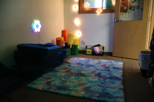 Calm corner with a soft rug, foam blocks and low lighting in the Hand in Hand ABA sensory room